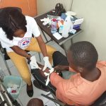 Photograph of a health worker preparing a vaccine dose at a community clinic.